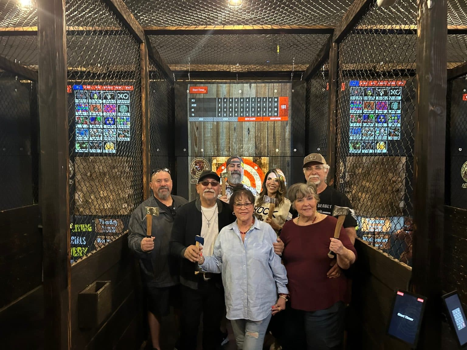 Group of friends holding axes in a projected axe throwing lane at Axe-Mania in Kingwood, TX